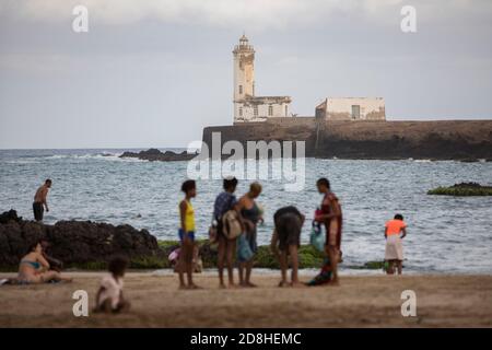 Les amateurs de plage nagent près d'un phare de l'îlot Santa Maria à Praia, Santiago, Cap-Vert. Banque D'Images