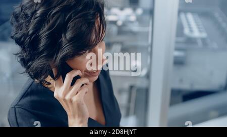 Prise de vue en grand angle d'une femme d'affaires réussie au bureau, passer un appel téléphonique important pour qu'elle puisse conclure la vente. Dans la vue d'arrière-plan avec Big City. Banque D'Images
