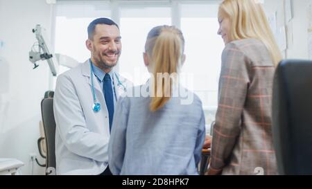 Mère avec sa petite fille mignon ont rendez-vous de docteur. Un pédiatre amical se met à sourire et écrit une ordonnance de la maladie. Moderne et lumineux Banque D'Images