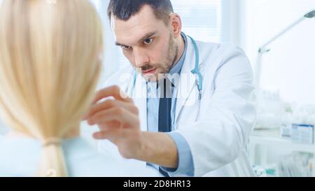 Prise de vue au-dessus de l'épaule d'une patiente assise patiemment tandis que le chirurgien plasticien dessine des lignes sur son visage pour l'opération de Facelift. Banque D'Images