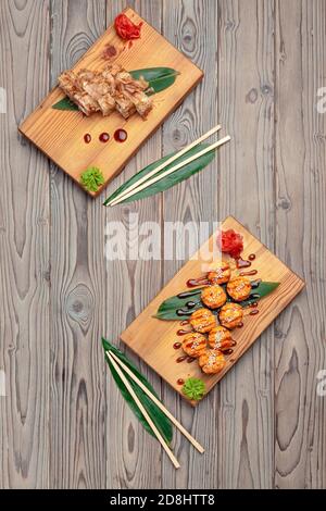 Petits pains à sushis servis sur des planches sur fond de bois sombre Banque D'Images