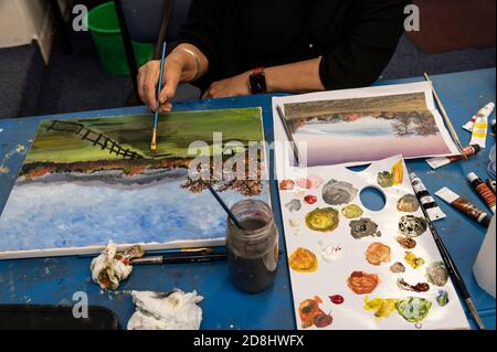 Artiste étudiant utilisant son pinceau, peignant une image à l'aide de peintures acryliques pendant une leçon d'art Banque D'Images