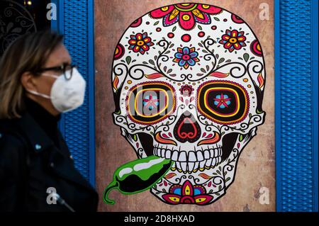 Madrid, Espagne. 30 octobre 2020. Une femme portant un masque facial protecteur marchant à côté d'un crâne mexicain décoré du jour des morts comme gouvernement espagnol a prolongé l'état d'alarme jusqu'au 9 mai pour contenir la deuxième vague de pandémie du coronavirus (Covid-19) suite à une autre augmentation des cas. Credit: Marcos del Mazo/Alay Live News Banque D'Images