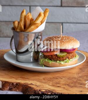 Hamburger de soja végétalien au petit pain avec salade et relish, et frites sur le côté. Vue verticale. Banque D'Images