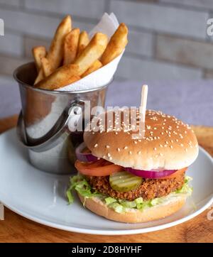 Hamburger de soja végétalien au petit pain avec salade et relish, et frites sur le côté. Banque D'Images