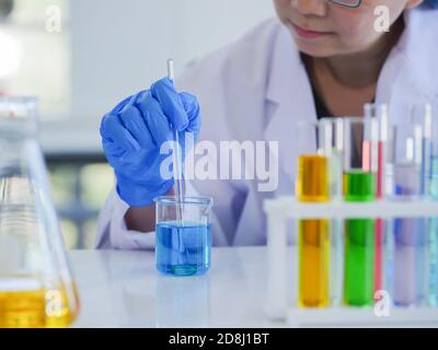 Les scientifiques féminins seniors mélangent une solution liquide dans un bécher à des fins biologiques, chimiques, pharmaceutiques, alimentaires ou autres. À mee Banque D'Images