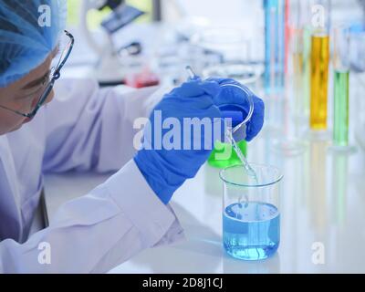 Femmes scientifiques senior travaillant en laboratoire se préparer à mélanger deux types de liquide dans un bécher pour des expériences scientifiques. Parmi une variété d'outils Banque D'Images