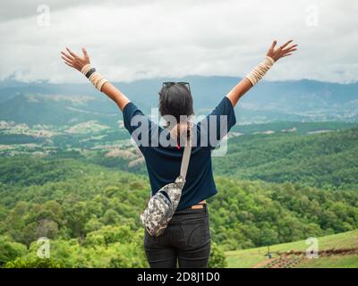 Portrait d'une femme regardant la vue panoramique de la gamme de la montagne, de la vallée et de la nature avec les bras levés Banque D'Images