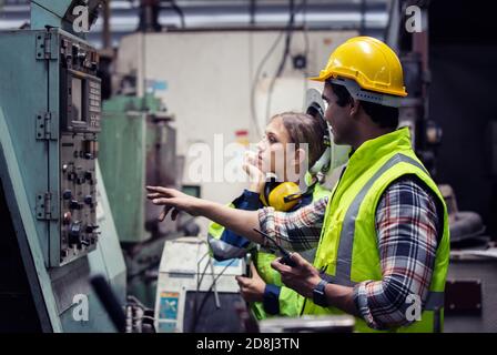 Hommes et femmes travaillant en usine sur la machine dans l'atelier. Banque D'Images