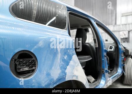 Réparation de la carrosserie, application PuTTY gros plan. Le mécanicien répare la voiture. Travailler après l'accident en travaillant le primaire de ponçage avant de peindre. Banque D'Images