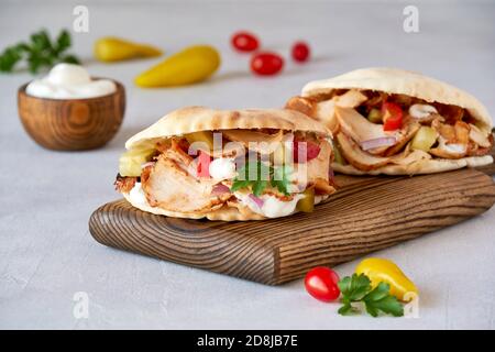 Shawarma avec sauce au poulet et à l'ail dans du pain pita sur une planche de bois. Gros plan Banque D'Images