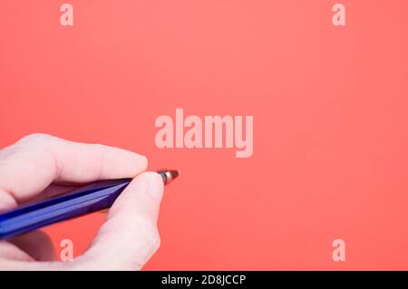 Main tenant un stylo sur fond rouge pour une copie espace Banque D'Images
