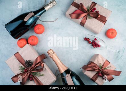 Bonne année et joyeux Noël, cadeaux, bouteille d'alcool, mandarines et verres à vin sur fond clair. Banque D'Images