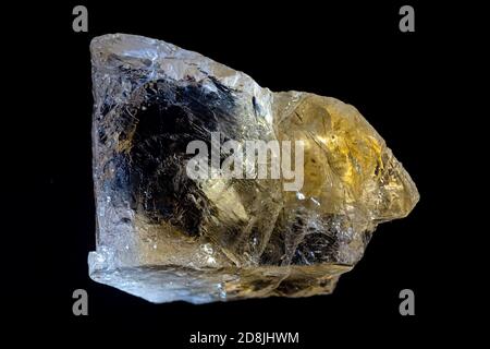 Gros plan d'un morceau de quartz citrine naturel, pierre brute jaune sur fond noir.le cristal clair et transparent crée des illusions optiques. Banque D'Images