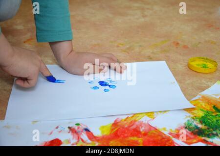 un enfant dessine. un enfant dessine des encres, des peintures à doigts, des empreintes à la main avec son doigt sur du papier blanc Banque D'Images