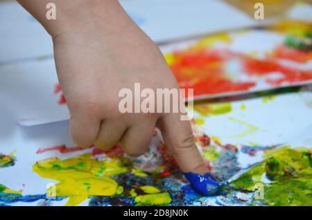 un enfant dessine. un enfant dessine des encres, des peintures à doigts, des empreintes à la main avec son doigt sur du papier blanc Banque D'Images