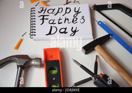 Inscription « Happy Pather's Day » avec outils de travail sur fond blanc. Salutations et cadeaux Banque D'Images