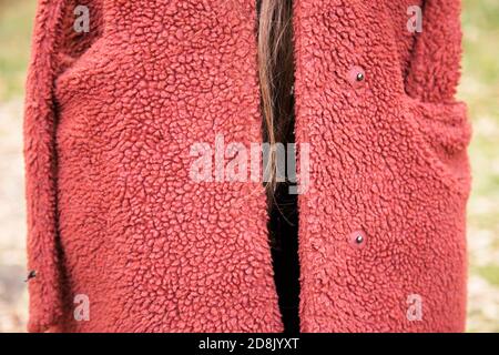 Jeune femme portant un grand polaire rouge comme manteau d'hiver, avec fil de cheveux brun suspendu Banque D'Images