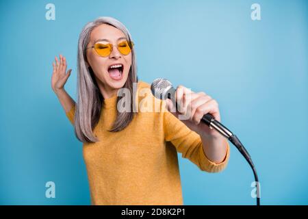 Gros plan photo de la charmante vieille dame chanteuse holding microphone ouvert bouche proche des yeux chantant les dernières notes chorus amour morceau de vêtements Banque D'Images