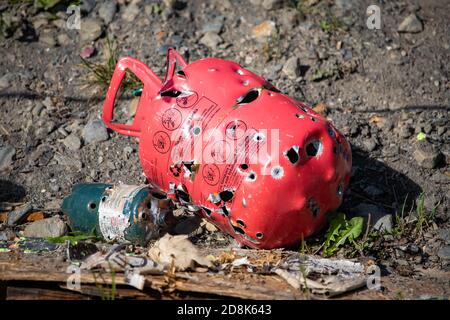 Réservoir de gaz en métal rouge avec trous de balle de la cible arrière-cour pratique Banque D'Images