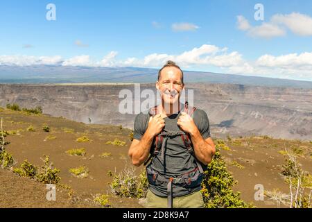 L'homme touristique du volcan d'Hawaï au cratère de Halemaumau dans la caldera de Kilauea dans le parc national des volcans d'Hawaï, grande île avec des nuages volcaniques et des cendres de Banque D'Images