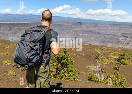 L'homme touristique du volcan d'Hawaï au cratère de Halemaumau dans la caldera de Kilauea dans le parc national des volcans d'Hawaï, grande île avec des nuages volcaniques et des cendres de Banque D'Images