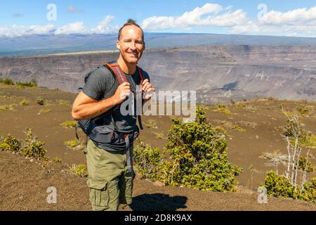 L'homme touristique du volcan d'Hawaï au cratère de Halemaumau dans la caldera de Kilauea dans le parc national des volcans d'Hawaï, grande île avec des nuages volcaniques et des cendres de Banque D'Images