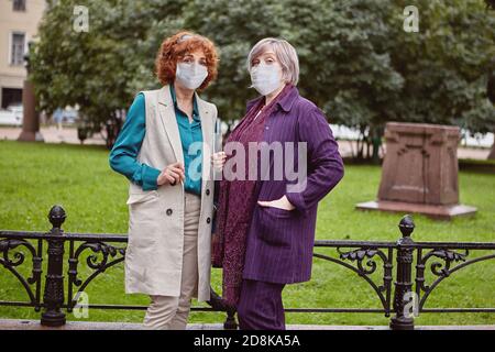 Les femmes matures attirantes dans les masques faciaux marche pendant la pandémie de Covid-19. Banque D'Images