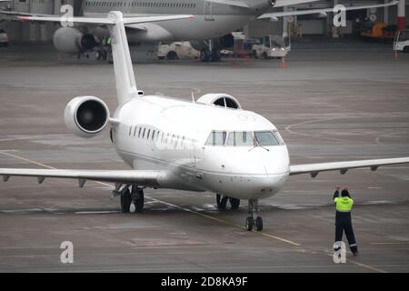 Avion de ligne régional moderne sur le tablier de l'aéroport. L'équipage au sol du contrôleur de trafic d'aéroport donne des commandes à un avion. Banque D'Images