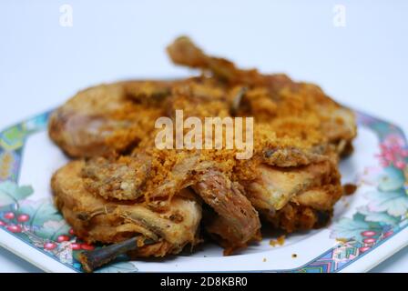 Poulet frit avec des flocons épicés croustillants sur fond blanc. Poulet frit indonésien ou ayam goreng kremes. Banque D'Images