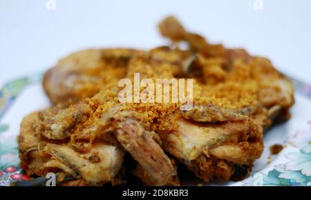 Poulet frit avec des flocons épicés croustillants sur fond blanc. Poulet frit indonésien ou ayam goreng kremes. Banque D'Images