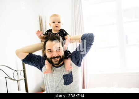 Jeune père heureux jouant avec bébé au lit Banque D'Images
