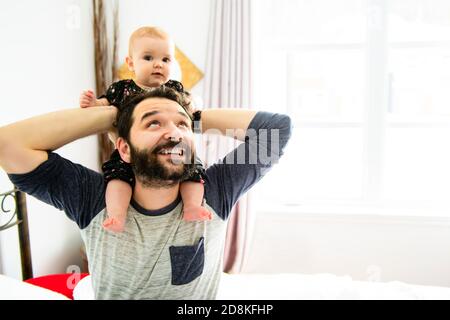 Jeune père heureux jouant avec bébé au lit Banque D'Images