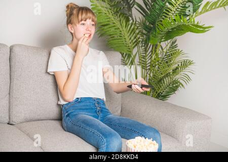 Un bon adolescent regardant la télévision et mangeant du pop-corn à la maison Banque D'Images