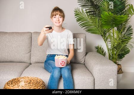 Un bon adolescent regardant la télévision et mangeant du pop-corn à la maison Banque D'Images