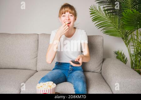 Un bon adolescent regardant la télévision et mangeant du pop-corn à la maison Banque D'Images