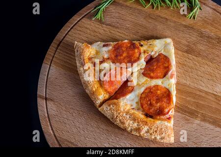 Une tranche de pepperoni Pizza se trouve sur une planche à découper en bois sur fond sombre. Quatre saveurs différentes de pizza. Espace pour le texte. La vue de à Banque D'Images