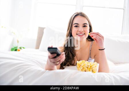 A young teenager watching movies in bed with popcorn Stock Photo