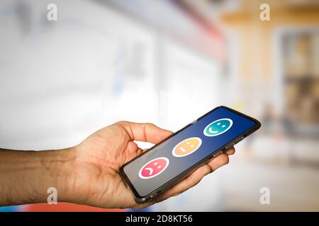 Homme donnant un sourire Emoticon Rating, positive Review via smartphone. Satisfaction des clients. Banque D'Images