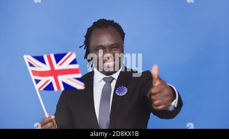 Jeune homme noir afro-américain portant le drapeau britannique de l'ue et montrant le pouce vers le haut. Photo de haute qualité Banque D'Images