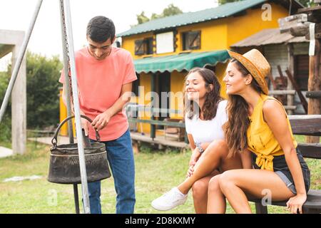 Des amis qui cuisinez à l'extérieur dans un ancien pot rétro. S'amuser dans un ranch. Ranch concept Photographie Banque D'Images