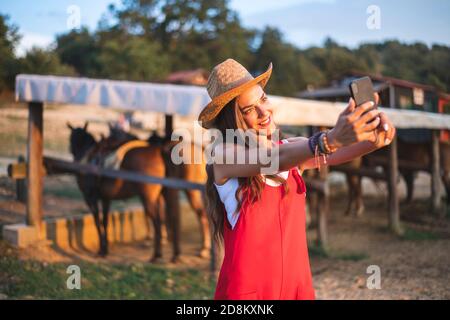 Souriante belle jeune femme appréciant sur la campagne à la ferme équestre et faire Selfie. Ranch concept Photographie Banque D'Images