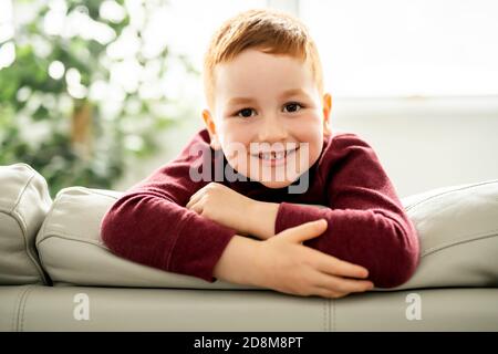 redhead enfant assis sur le canapé à la maison Banque D'Images