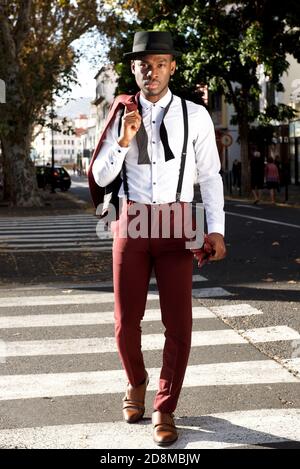 Portrait complet du beau modèle de mode homme noir marchant en ville avec costume Banque D'Images
