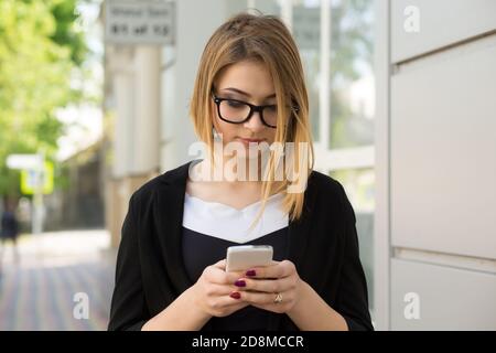 Pensive attrayante femme tendance fille à l'extérieur près du bureau de magasin de centre commercial texting, l'envoi d'un message, la navigation dans Internet et profil de médias sociaux, Banque D'Images