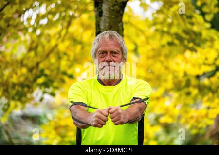 Un homme de la fin des années 60 s'exerce à l'extérieur avec un groupe de résistance en automne. Banque D'Images