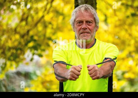 Un homme de la fin des années 60 s'exerce à l'extérieur avec un groupe de résistance en automne. Banque D'Images