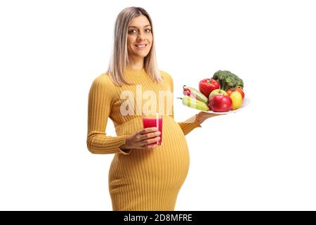 Femme enceinte tenant une assiette de fruits et légumes et un jus frais isolé sur fond blanc Banque D'Images