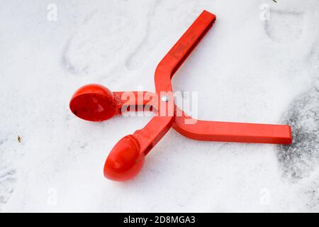 Dispositif en plastique rouge vif, clip de jouet pour faire des boules de neige sur fond de neige blanc. Concept de jeu amusant d'hiver et d'enfance heureux. Banque D'Images