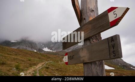 Vue rapprochée de la signalisation en bois et du marquage des sentiers montrant les directions de Rescher Alm et Piz LAD dans le Tyrol du Sud avec des montagnes couvertes de nuages. Banque D'Images